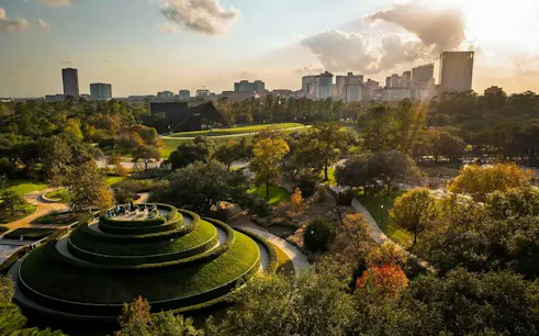 Houston Museum District park with spiral hill and city skyline in the background.