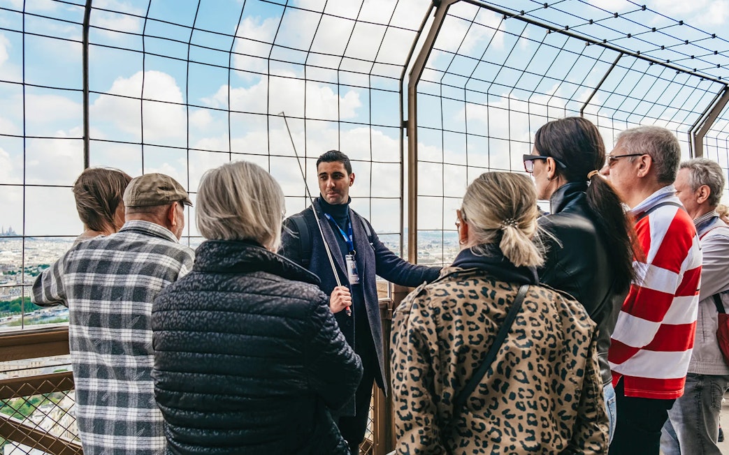 Tour guide explaining to a group on the Eiffel Tower's viewing platform, Paris.