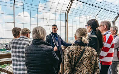 Tour guide explaining to a group on the Eiffel Tower's viewing platform, Paris.