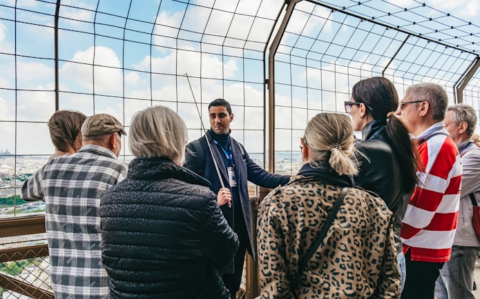 Tour guide explaining to a group on the Eiffel Tower's viewing platform, Paris.