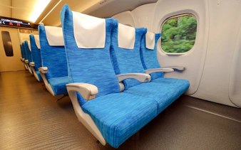Shinkansen train seats with view of greenery through window.