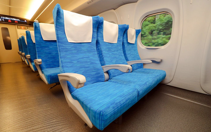 Shinkansen train seats with view of greenery through window.