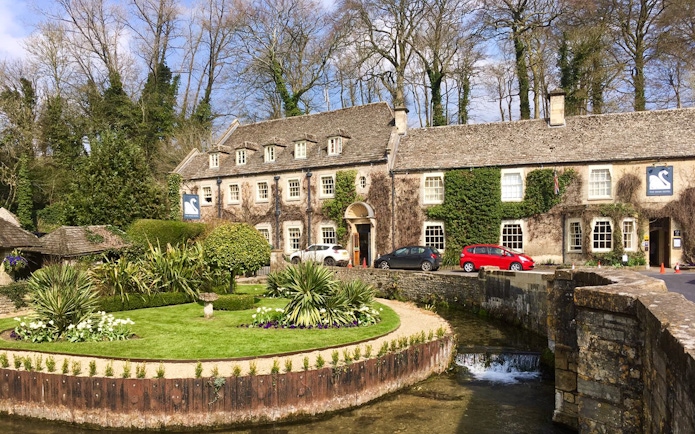 Cotswolds stone building with ivy, garden, and stream in front, near Broadway Tower, England.