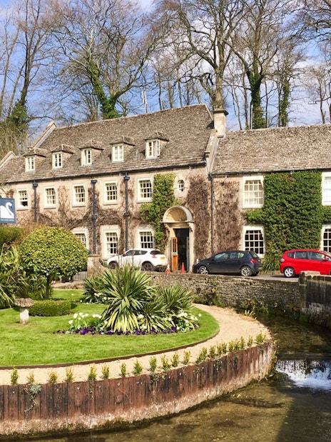Cotswolds stone building with ivy, garden, and stream in front, near Broadway Tower, England.