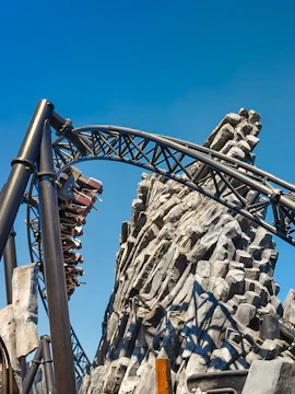 Roller coaster on steep track at Phantasialand with rocky backdrop.