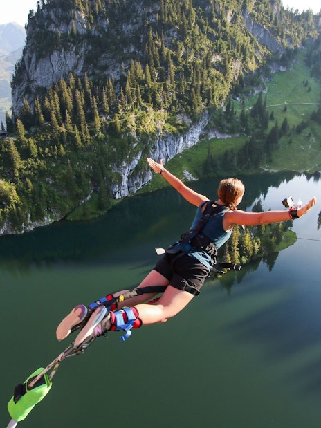 Person bungee jumping over Stockhorn Lake, Interlaken, surrounded by mountains.