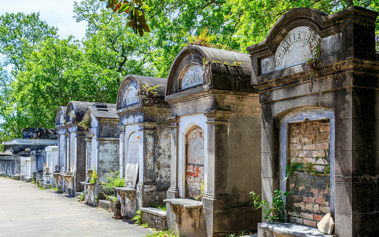 Weathered tombs in Lafayette Cemetery, New Orleans, with greenery in the background.