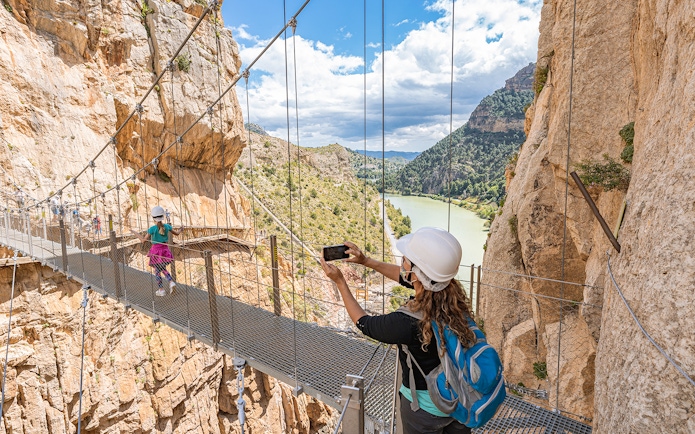 Visitors crossing suspension bridge on Caminito del Rey trail, Málaga, Spain.