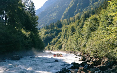 River rafting on a rapid in Interlaken surrounded by lush green forest and mountains.