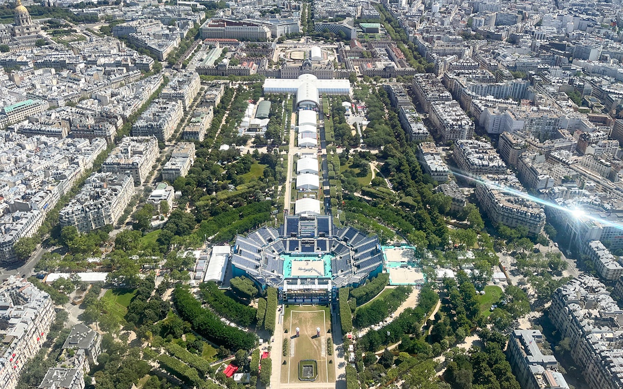 Aerial view of Paris cityscape with gardens and buildings, seen from the Eiffel Tower.