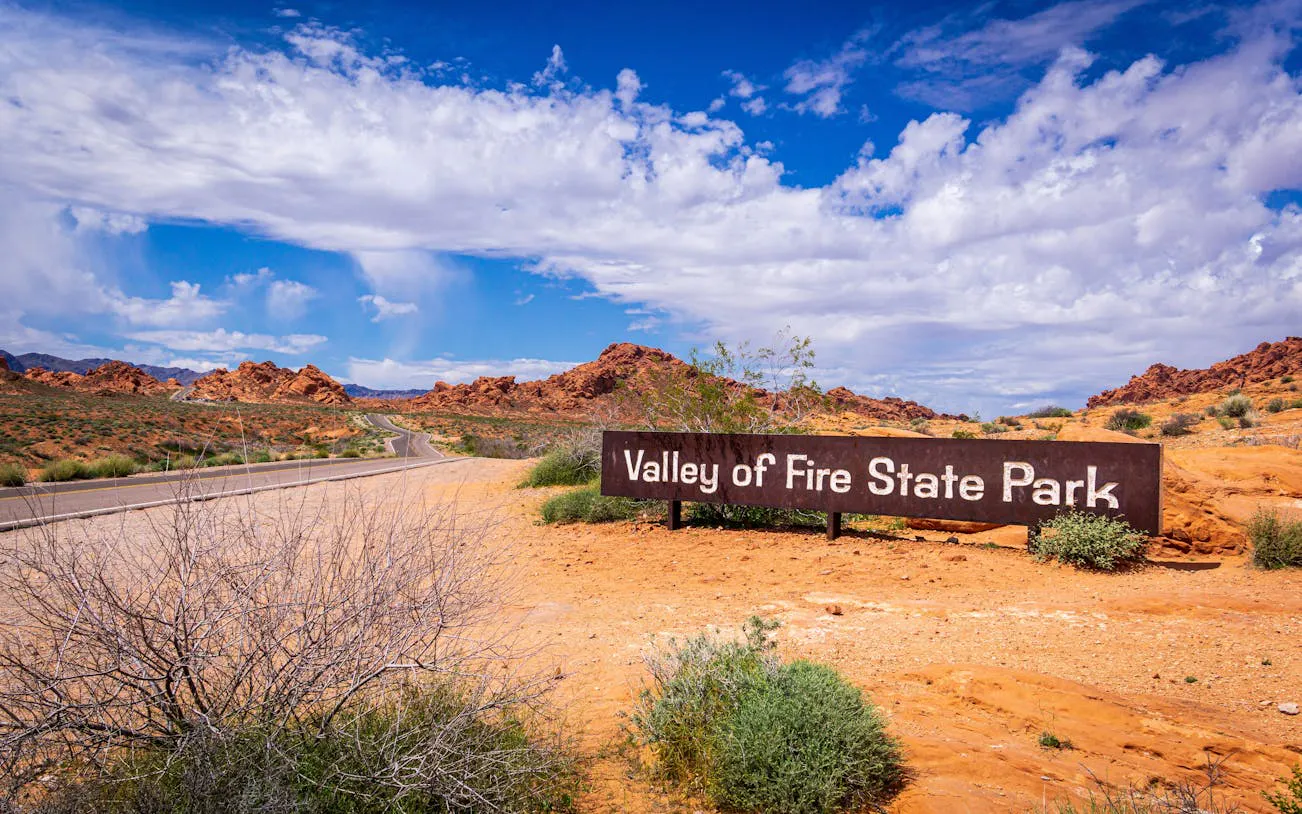 Valley of Fire State Park entrance sign with desert landscape and road in Nevada.