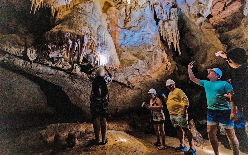 Tourists exploring a cave with stalactites on James Bond Island, Phang Nga Bay.
