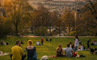 People relaxing in a Prague park during sunset, part of the Czech it Out Prague Pub Crawl tour.