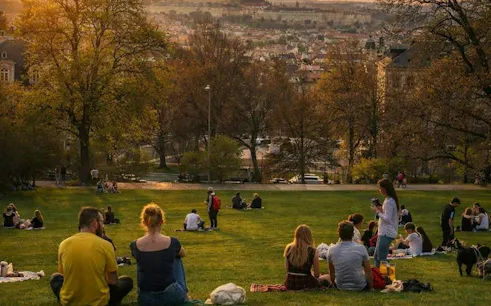 People relaxing in a Prague park during sunset, part of the Czech it Out Prague Pub Crawl tour.