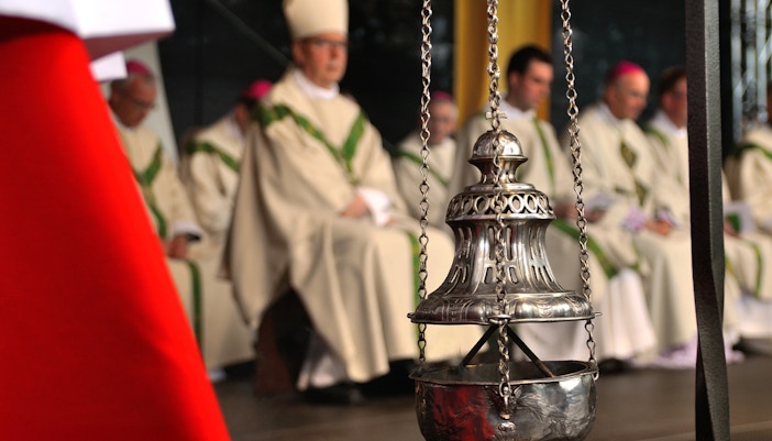 Incense burner swinging during a church service in a historic cathedral.