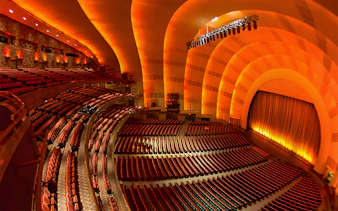 Interior of Radio City Music Hall with empty seats and illuminated stage.