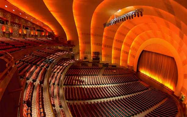 Interior of Radio City Music Hall with empty seats and illuminated stage.
