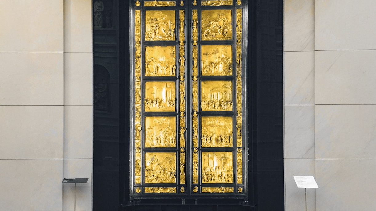 Bronze door with intricate panels at Opera del Duomo Museum, Florence.