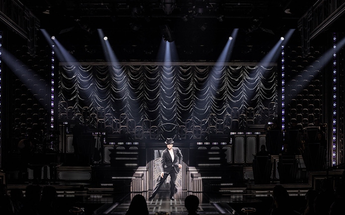 Performer on stage in spotlight during a theatrical show, "Just In Time.