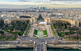 Panoramic view of Paris from Eiffel Tower Summit, featuring Trocadéro Gardens and cityscape.