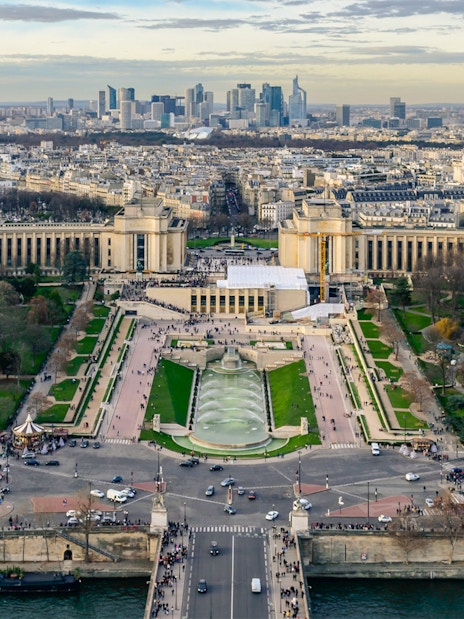 Panoramic view of Paris from Eiffel Tower Summit, featuring Trocadéro Gardens and cityscape.