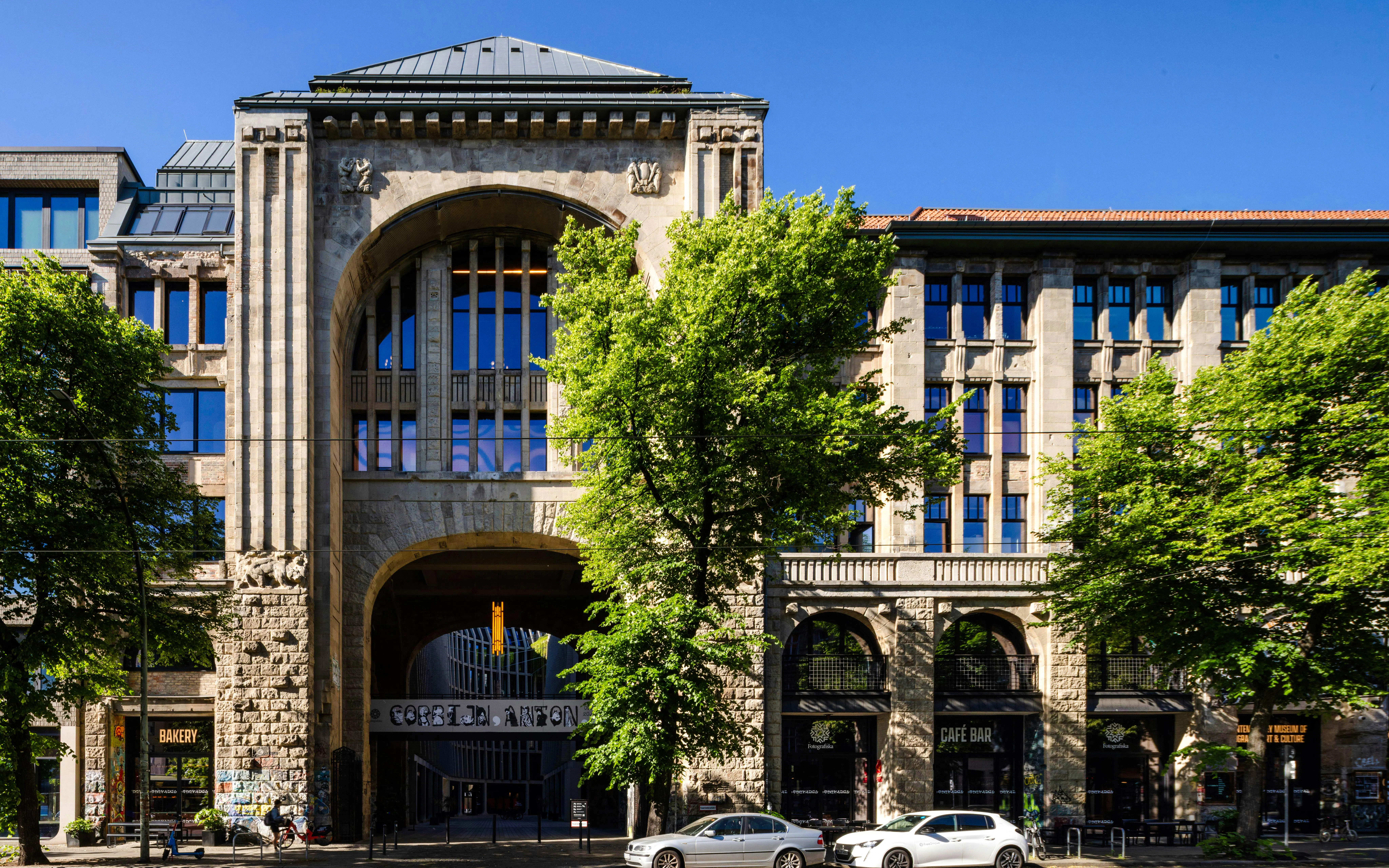 Exterior of Fotografiska Berlin with arched entrance and surrounding trees.