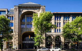 Exterior of Fotografiska Berlin with arched entrance and surrounding trees.