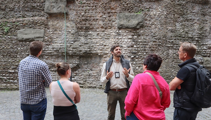 Guide explaining history at Castel Sant'Angelo, Rome, with tourists listening attentively.