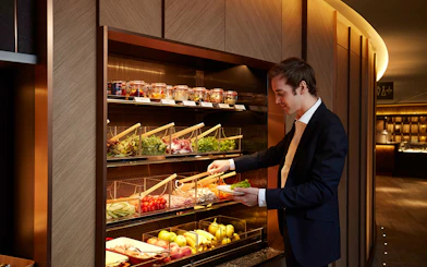 Man selecting fresh salad at Hong Kong International Airport first-class lounge.