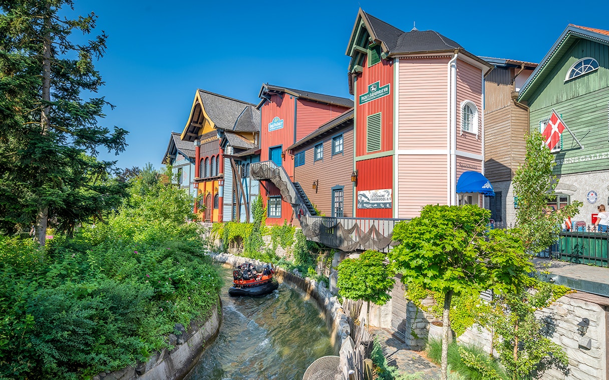 Group enjoying a thrilling Fjord Rafting ride past colorful buildings and lush greenery.