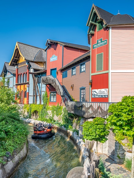 Group enjoying a thrilling Fjord Rafting ride past colorful buildings and lush greenery.