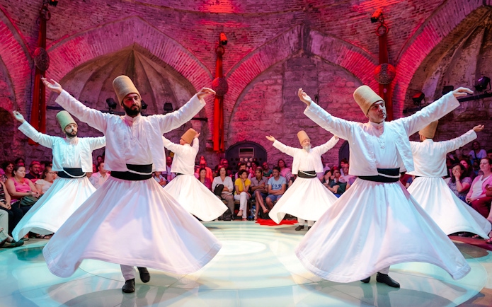 Whirling Dervishes performing in a historic venue with an audience in Istanbul.