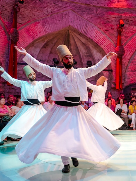 Whirling Dervishes performing in a historic venue with an audience in Istanbul.