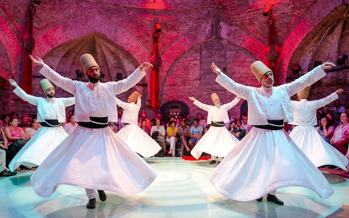 Whirling Dervishes performing in a historic venue with an audience in Istanbul.