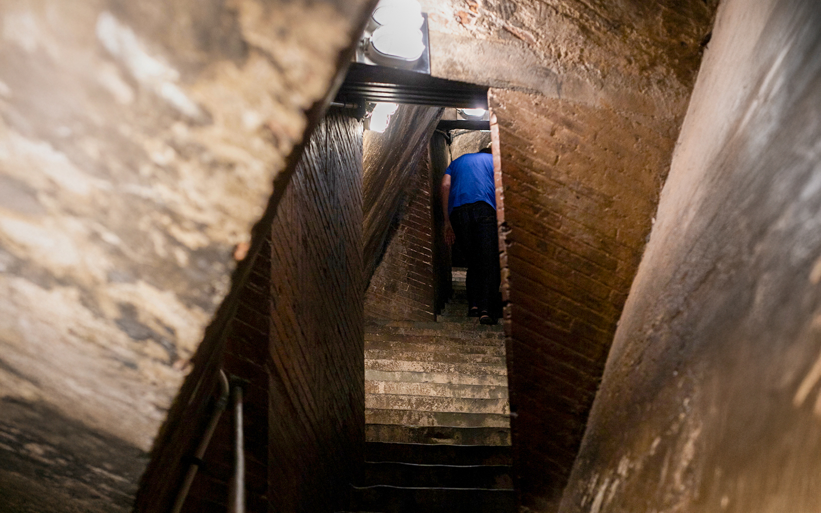 Inner stairs of Florence Cathedral dome with a person ascending.