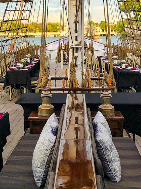 Dinner tables set on the deck of The Royal Albatross for a sunset cruise.