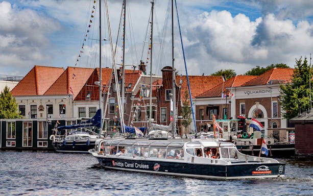 Cruise boat on Haarlem canal with historic buildings in the background.