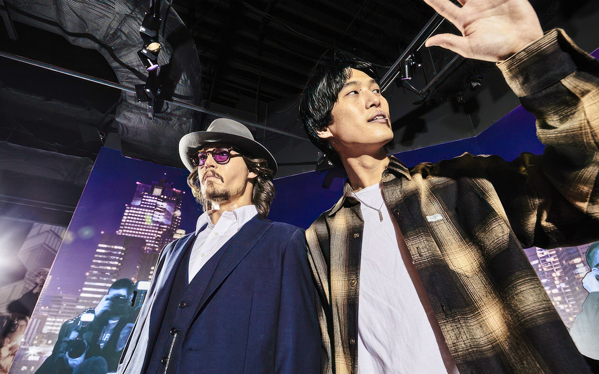 Wax figure exhibit at Madame Tussauds Tokyo with cityscape backdrop.
