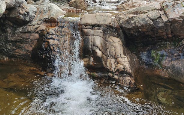 Waterfall flowing over rocks in Rio Pitrisconi during San Teodoro Jeep Tour.