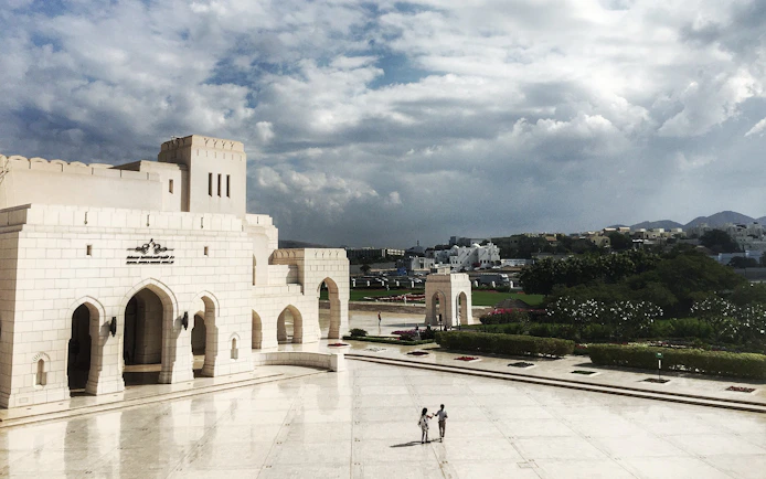 Royal Opera House Muscat exterior with visitors walking in the courtyard.