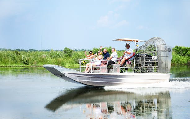 Airboat tour with people exploring a swamp in New Orleans.