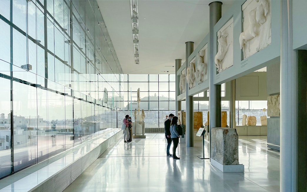 Visitors exploring sculptures inside Acropolis Museum, Athens.