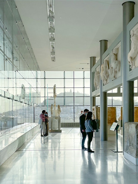 Visitors exploring sculptures inside Acropolis Museum, Athens.