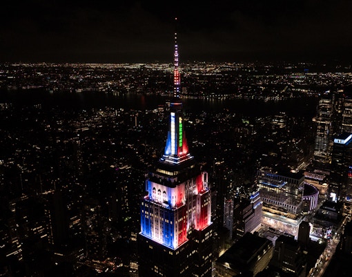 Empire State Building with Christmas-themed tower lights in New York City skyline.