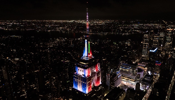 Empire State Building with Christmas-themed tower lights in New York City skyline.