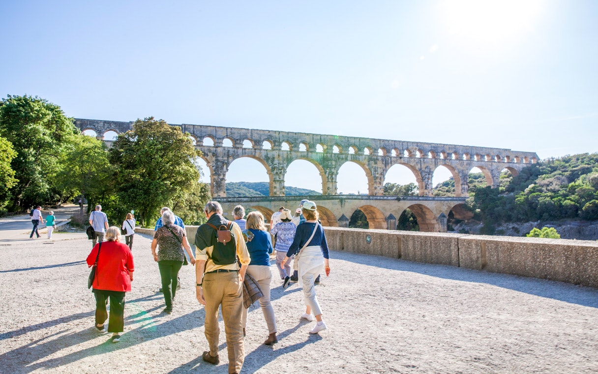 Visitors walking towards Pont du Gard aqueduct in France.