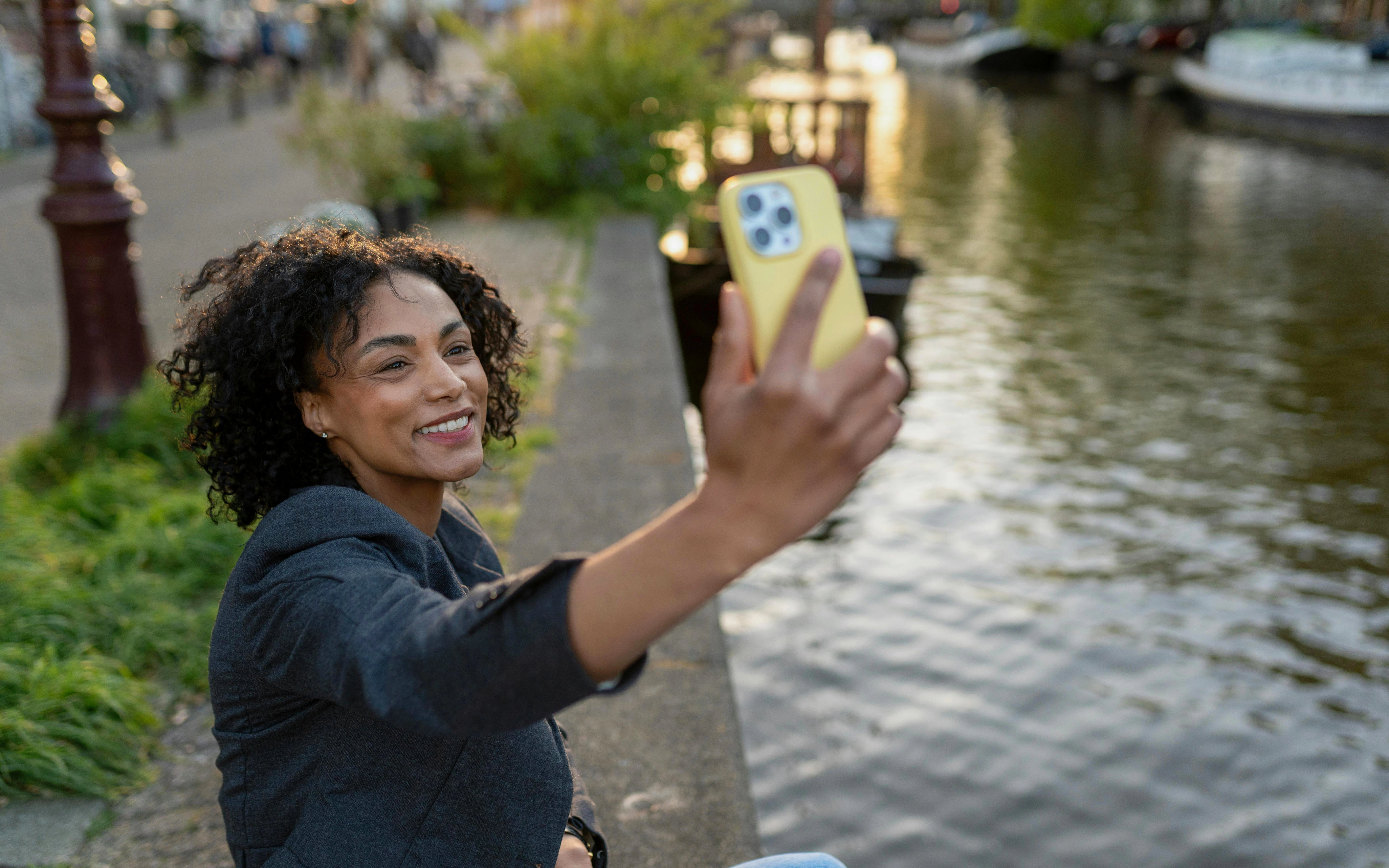 Woman taking selfie by Amsterdam canal.