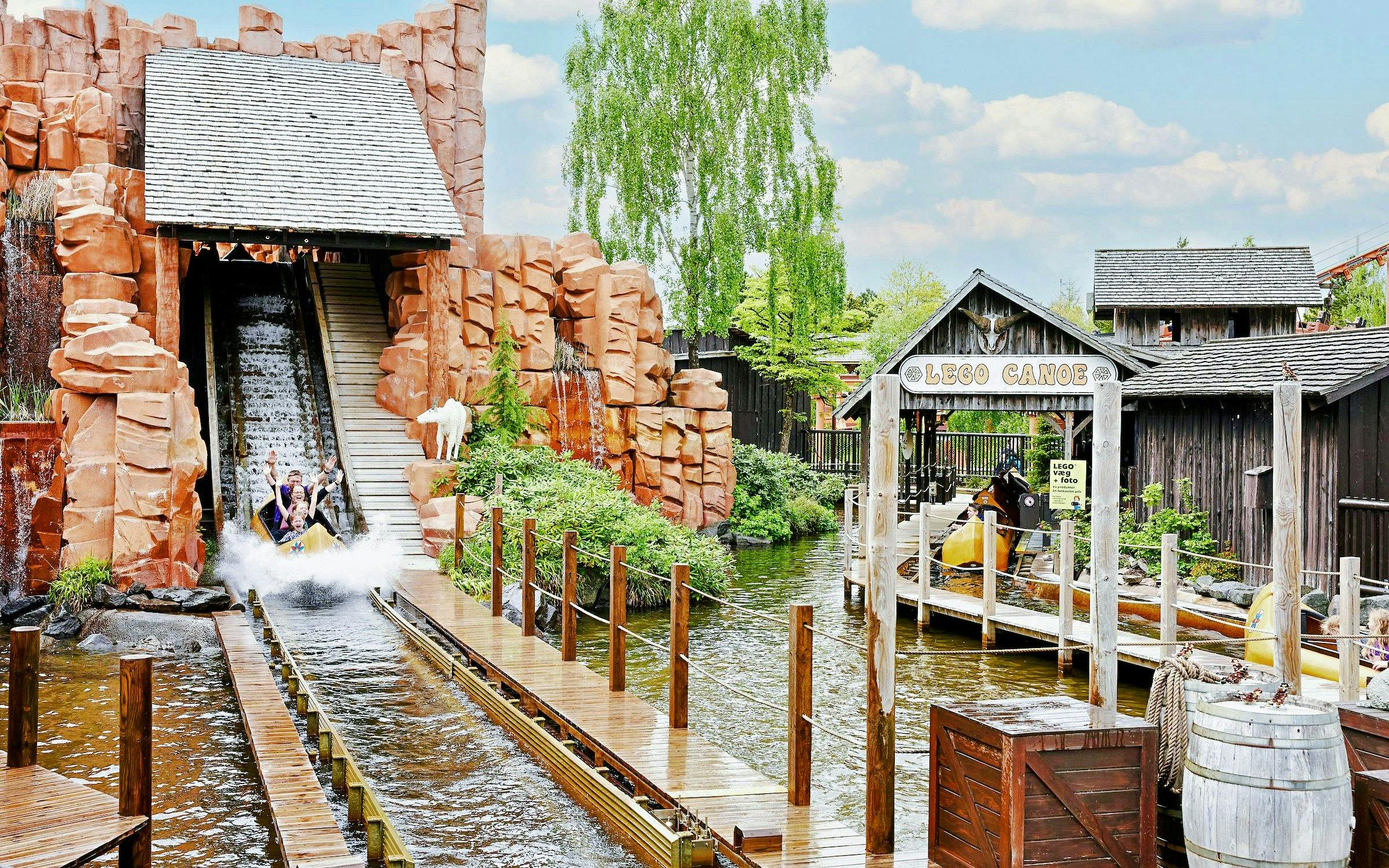 Visitors enjoying a water ride at LEGOLAND® Billund with LEGO Canoe sign.