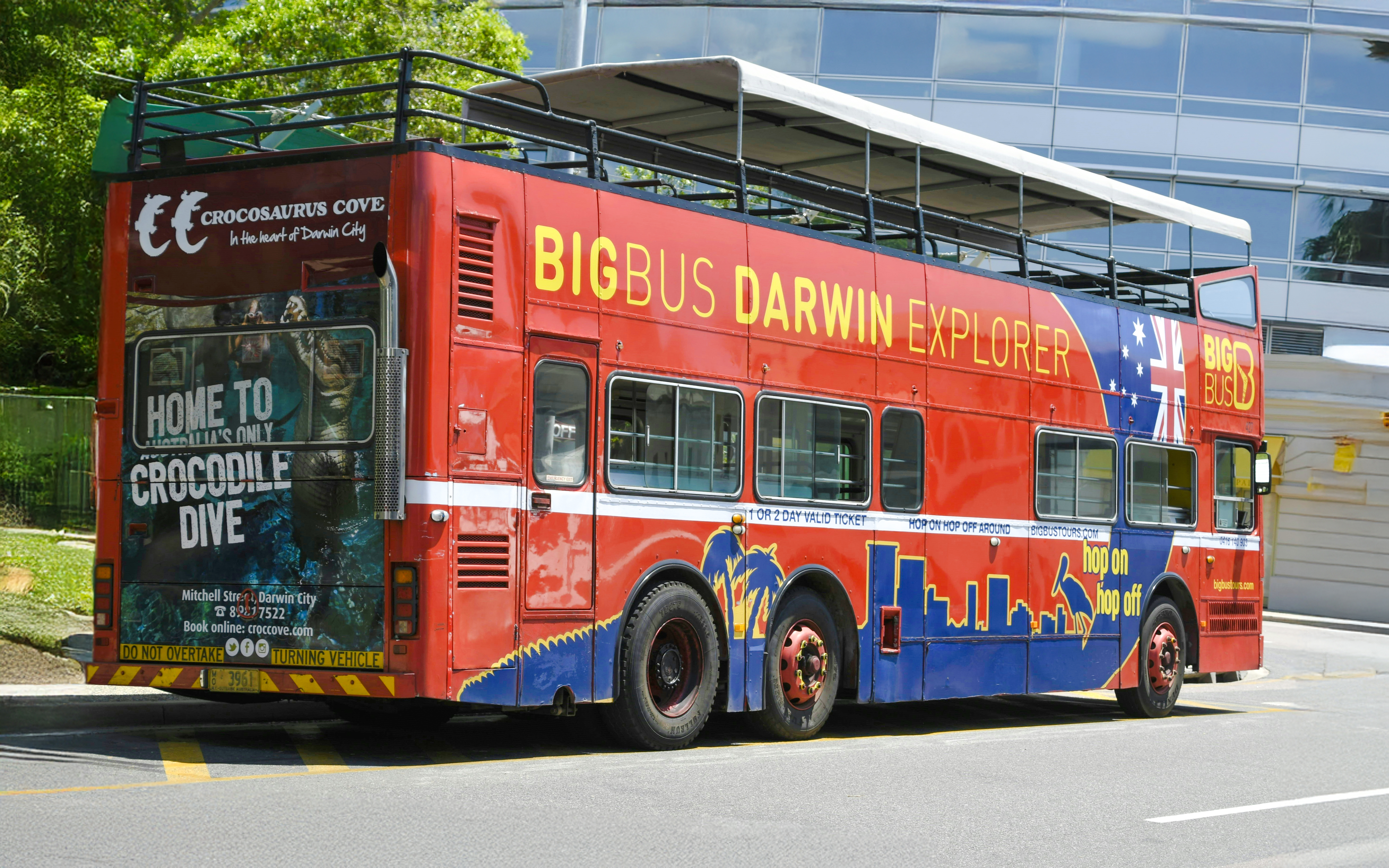 Big Bus Darwin Explorer parked near Crocosaurus Cove, promoting hop on hop off tours.
