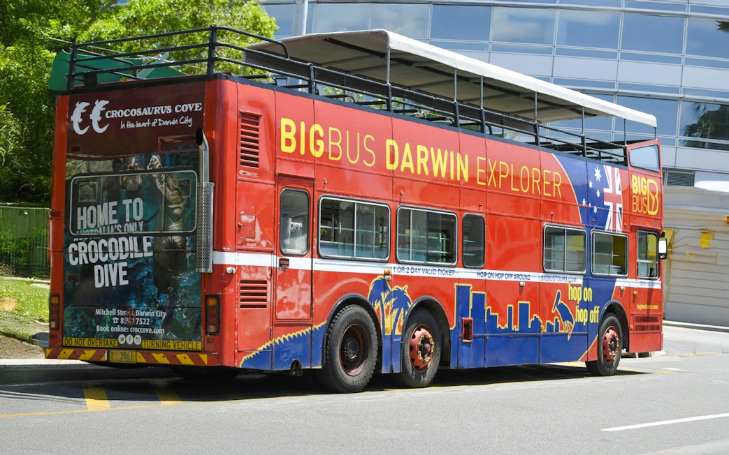 Big Bus Darwin Explorer parked near Crocosaurus Cove, promoting hop on hop off tours.